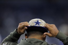 A player puts on a ball cap with the Dallas Cowboys logo in camouflage style before an NFL football game against the Philadelphia Eagles on Sunday, Nov. 8, 2015, in Arlington, Texas. (AP Photo/Brandon Wade)