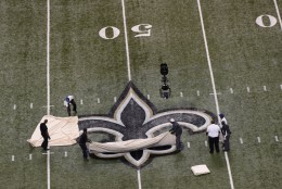 Workers pull a tarp off the the fleur de lis, the New Orleans Saints logo, before an NFL football game between the New Orleans Saints and the Philadelphia Eagles at the Mercedes-Benz Superdome in New Orleans, Monday, Nov. 5, 2012. (AP Photo/Bill Feig)