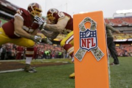 Washington Redskins players warm up behind the goal line marker with the NFL's Salute to Service logo attached before an NFL football game against the Tampa Bay Buccaneers in Landover, Md., Sunday, Nov. 16, 2014. (AP Photo/Patrick Semansky)