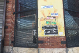 A sign that reads "we must stop killing each other" is seen near the site of the Baltimore riots a year later. (WTOP/Mike Murillo)
