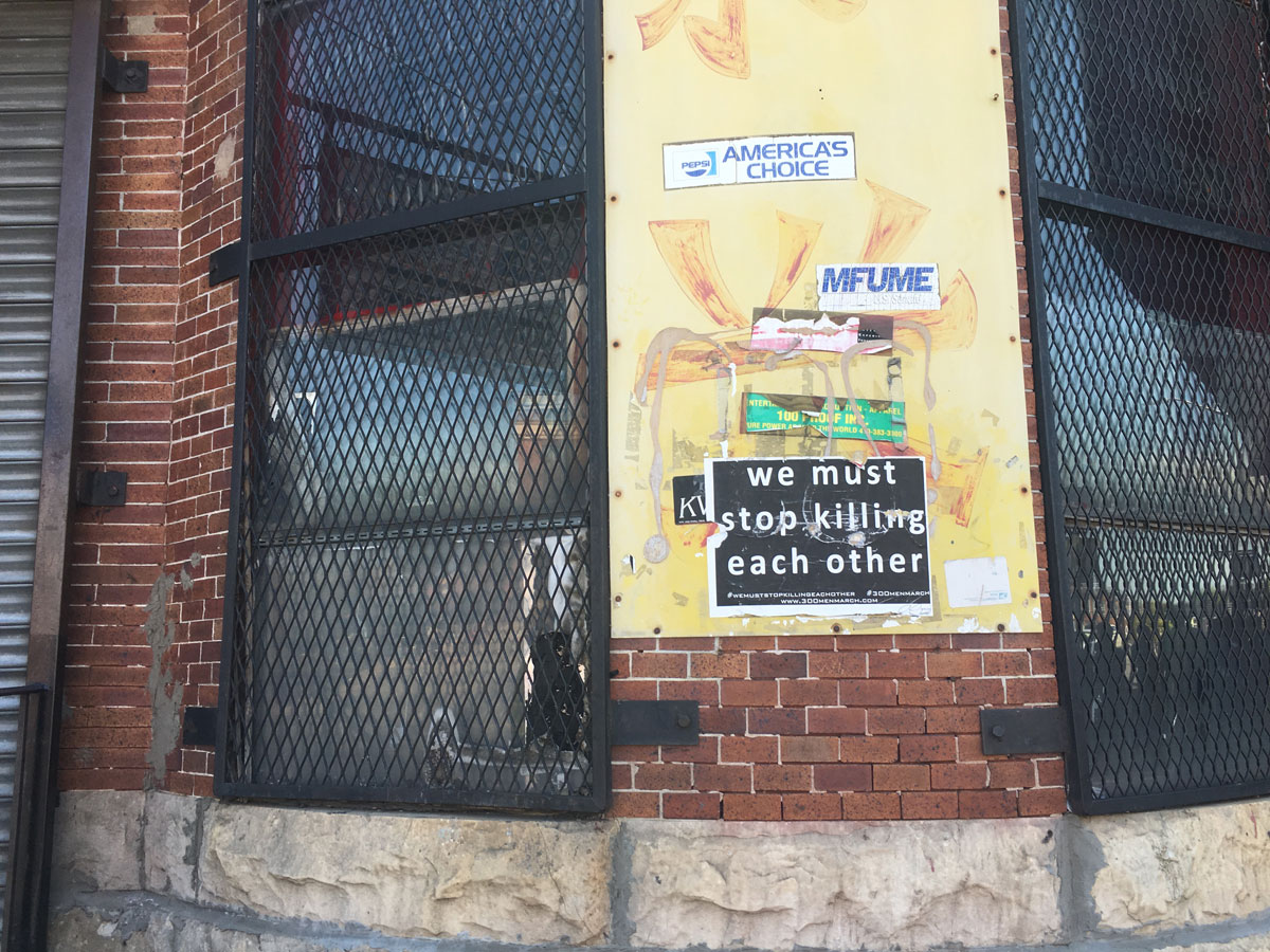 A sign that reads "we must stop killing each other" is seen near the site of the Baltimore riots a year later. (WTOP/Mike Murillo)