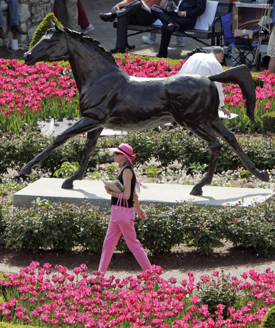 A horse racing fan makes her way past the statue of Aristide, the first Kentucky Derby winner, in the paddock area at Churchill Downs, Saturday morning, May 7, 2005, in Louisville, Ky. The Kentucky Derby is the 10th race of the day. (AP Photo/ Darron Cummings)