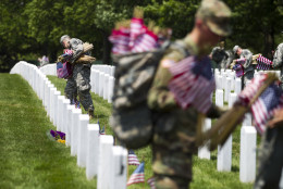 Members of the Old Guard with the Washington Memorial in the back, place flags in front of every headstone at Arlington National Cemetery in Arlington, Va., Thursday, May 26, 2016. Soldiers were to place nearly a quarter of a million American flags at the cemetery as part of a Memorial Day tradition. ( AP Photo/Jose Luis Magana)