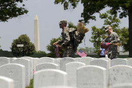 Members of the Old Guard with the Washington Memorial in the back, place flags in front of every headstone at Arlington National Cemetery in Arlington, Va., Thursday, May 26, 2016. Soldiers were to place nearly a quarter of a million American flags at the cemetery as part of a Memorial Day tradition. ( AP Photo/Jose Luis Magana)
