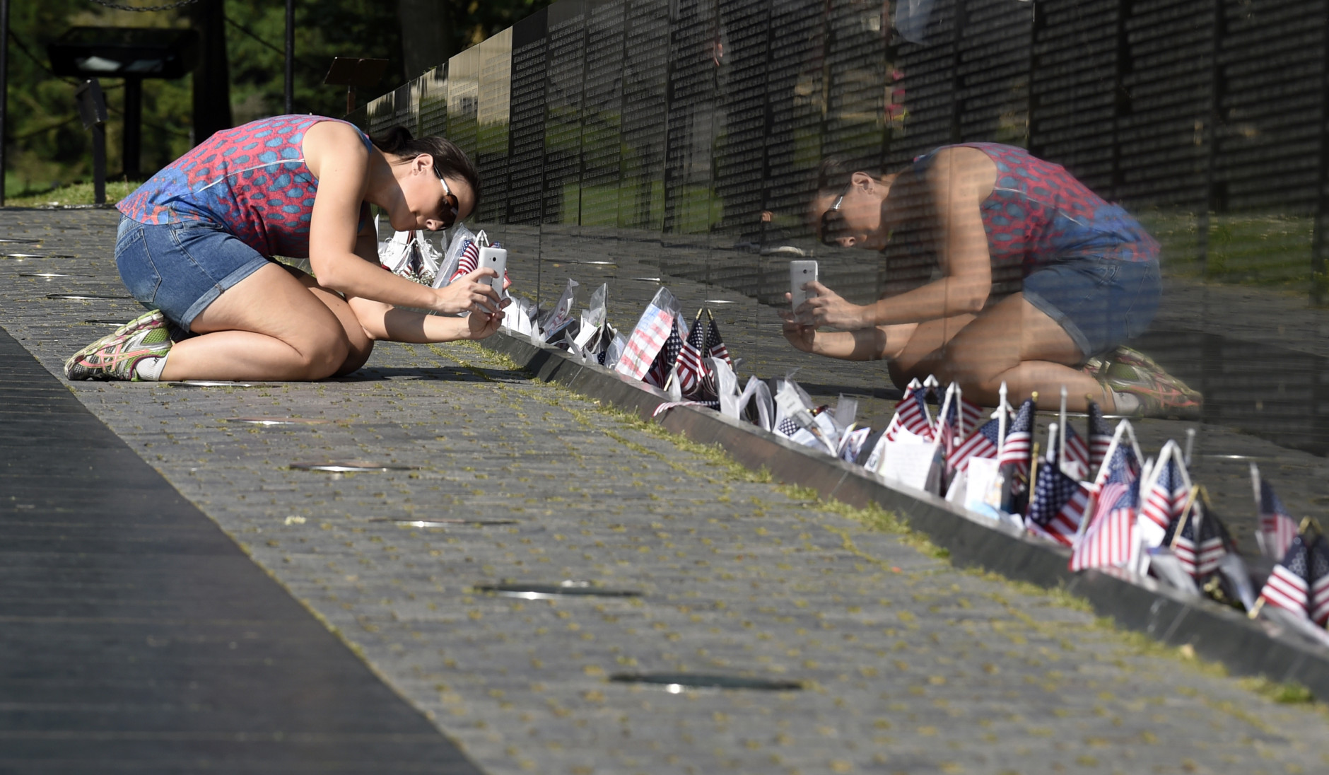 Gabriella Longo, from Porto Alegre, Brazil, takes a photo of the Vietnam Memorial in Washington, Friday, May 27, 2016,on the start of the Memorial Day weekend. (AP Photo/Susan Walsh)