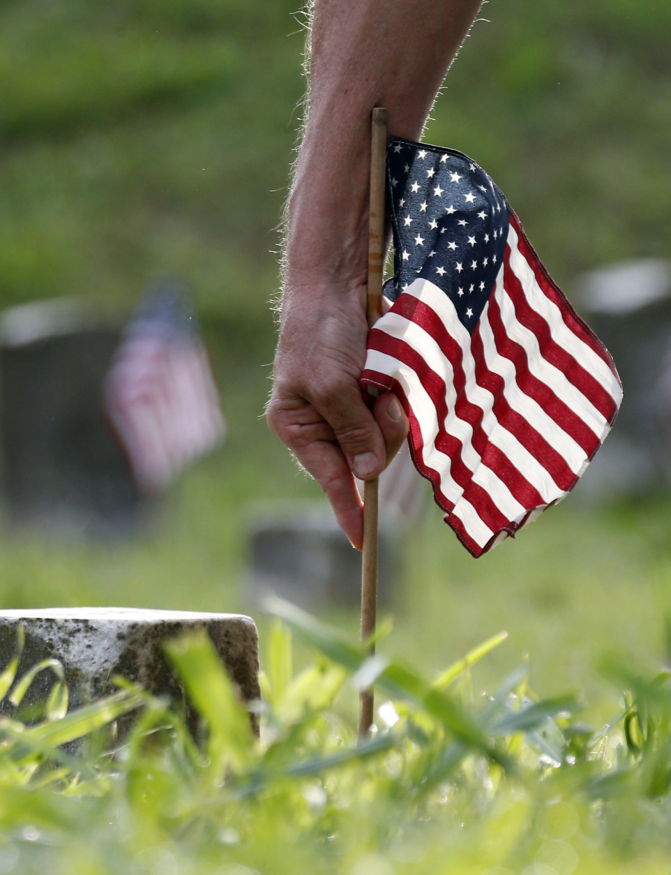 A volunteer plants an American flag, one of about 18,000, on the graves of American servicemen in the Vicksburg National Cemetery in Vicksburg, Miss., Friday, May 27, 2016, in advance of the Memorial Day weekend. Memorial Day is the only holiday the flags are placed on the graves, which include among others, 17,000 Civil War Union troops, two Confederate soldiers and a member of the Royal Australian Air Force. (AP Photo/Rogelio V. Solis)