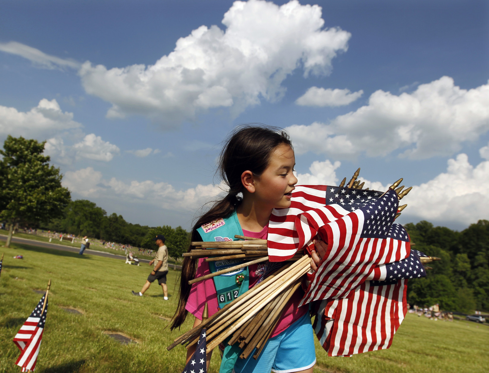 Girl Scout Megan Lontoc, 10, has her arms full of Flags as scouts placed thousands of flags on veteran's graves at Brig. Gen. William C. Doyle Veterans Memorial Cemetery in honor of Memorial Day, Friday, May 27, 2016, in Wrightstown N.J. (AP Photo/Mel Evans)
