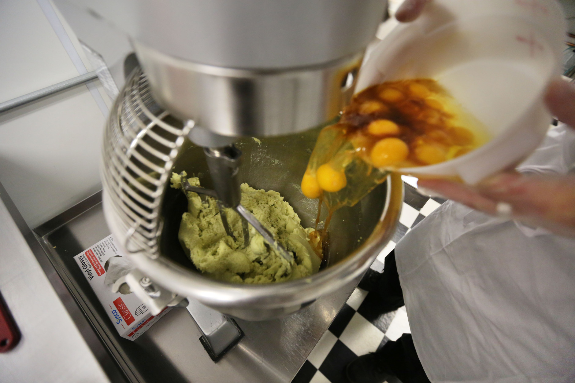 In this June 19, 2014 photo, eggs are added into a mixer with green cannabis-infused "canna butter" in a stainless steel bowl at the start of batter mixing for peanut butter jelly cups, inside Sweet Grass Kitchen, a well-established gourmet marijuana edibles bakery which sells its confections to retail outlets, in Denver. Sweet Grass Kitchen, like other cannabis food producers in the state, is held to rigorous health inspection standards, and has received praise from inspectors, according to owner Julie Berliner. (AP Photo/Brennan Linsley)