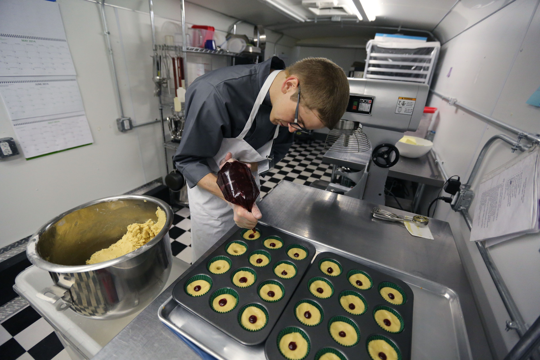 In this June 19, 2014 photo, chef Alex Tretter adds strawberry jam to cannabis-infused peanut butter and jelly cups before baking them, at Sweet Grass Kitchen, a well-established gourmet marijuana edibles bakery which sells its confections to retail outlets, in Denver. Sweet Grass Kitchen, like other cannabis food producers in the state, is held to rigorous health inspection standards, and has received praise from inspectors, according to owner Julie Berliner. (AP Photo/Brennan Linsley)