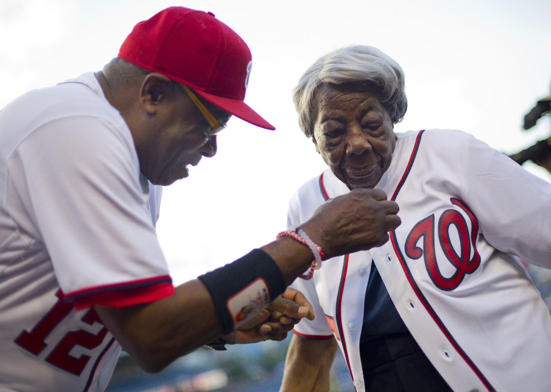Washington Nationals manager Dusty Baker helps Virginia McLaurin, 107, with her jersey on the field before the Nationals' baseball game against the St. Louis Cardinals at Nationals Park, Thursday, May 26, 2016, in Washington. McLaurin gained Internet fame for her impromptu dance with President Barack Obama in February during a Black History Month reception at the White House and said afterward that she could finally die happy. (AP Photo/Pablo Martinez Monsivais)