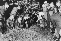 Newsmen and spectators are watching as a young man points to the spot where the body of 19-month-old baby Charles A. Lindbergh Jr., was found in a shallow grave, near Mount Rose, N.J., on May 12, 1932. The infant son of world-famed aviator Charles Lindbergh was kidnapped on March 1, 1932, and found dead today, only four-and-a-half miles away from the Lindbergh estate.  (AP Photo)