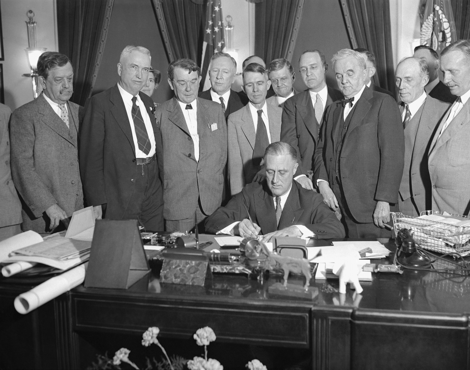 President Franklin D. Roosevelt signs the Norris-Hill Bill to develop the Tennessee Valley, May 18, 1933.  From left:  Sen. Ellison D. Smith of South Carolina; Rep. John J. McSwain of South Carolina; Sen. Kenneth D. McKellar of Tennessee; Rep. Samuel Davis McReynolds of Tennessee; Reps. Miles C. Allgood, William Bacon Oliver and Lister Hill, all of Alabama; Sen. George William Norris of Nebraska; and looking over his shoulder is Rep. Edward B. Almon, whose district is Muscle Shoals.  (AP Photo)
