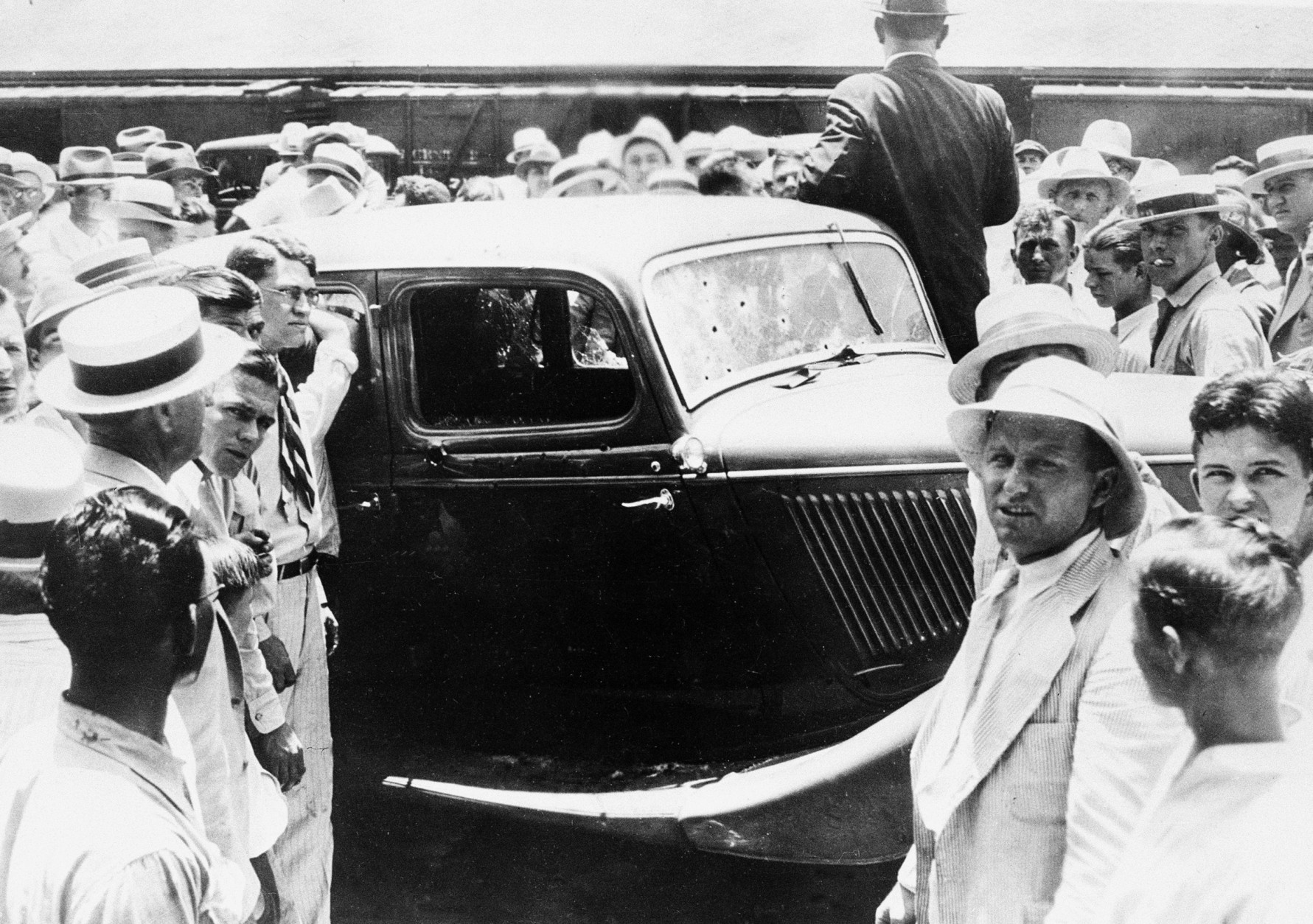 People crowd around the abandoned bullet-riddled 1934 Ford automobile in which Bonnie Parker and Clyde Barrows were killed by federal agents in Arcadia, La., May 23, 1934.  (AP Photo)