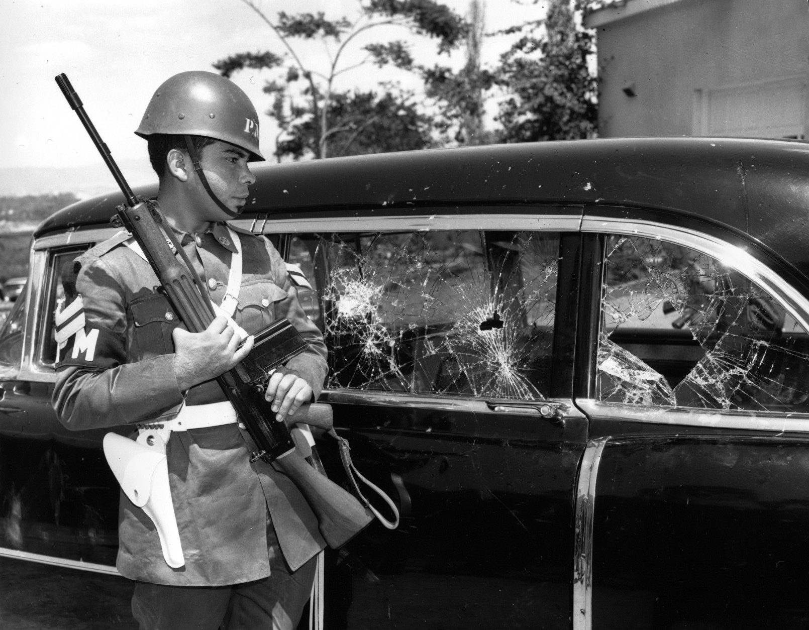 An armed guard stands by the car in which Vice President Richard Nixon rode through jeering, rock-throwing mobs May 13, 1958, in Caracas, Venezuela.  (AP Photo)