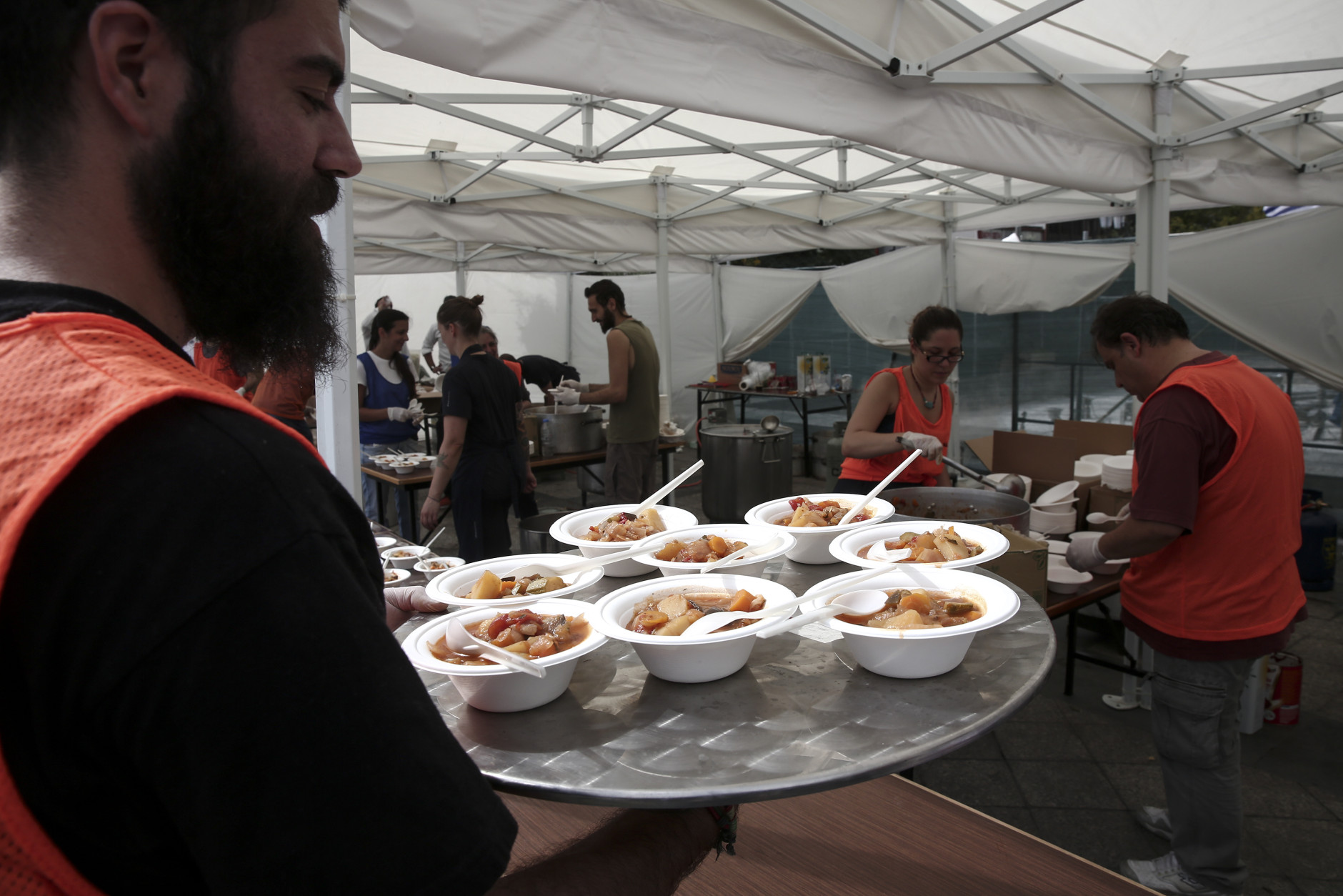 A volunteer serves meals cooked with 'wasted' produce deemed unsuitable by food stores because of their appearance, in Athens, Greece, Sunday Oct. 11, 2015. The event was part of the 'Feeding5000' campaign which aims to highlight the waste of foodstuff in advanced societies.   (AP Photo/Yorgos Karahalis)