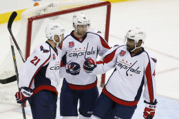 From left to right, former Washington Capitals' Brooks Laich, Eric Fehr and Joel Ward celebrate Laich's open-net goal against the New Jersey Devils during the third period of an NHL hockey game, Saturday, Dec. 6, 2014, in Newark, N.J. The Capitals won 4-1. (AP Photo/Julio Cortez)