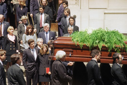 The casket bearing the remains of Jacqueline Kennedy Onassis is carried out of St. Ignatius Loyola Roman Catholic Church in New York following a funeral mass  Monday, May 23, 1994. Following immediately behind the pallbearers are John F. Kennedy Jr., with an arm around his sister, Caroline Kennedy Schlossberg; Caroline’s husband, Edwin Schlossberg, is visible between them. Hillary Rodham Clinton, left; Sen. Edward M. Kennedy (D-Mass.) and his wife, Victoria Reggie, center; and at right, third from bottom, Robert F. Kennedy Jr. (AP Photo/Elise Amendola)