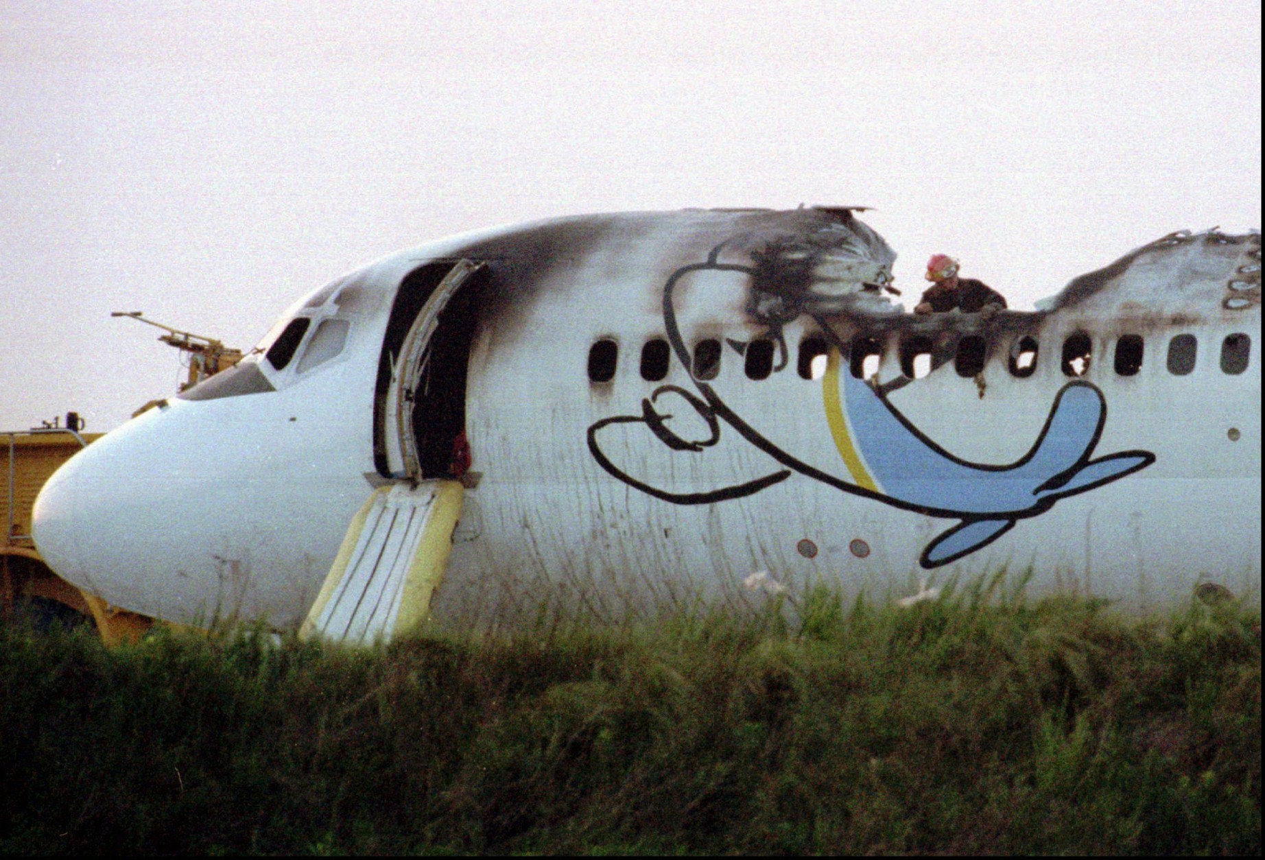 FILE--A firefighter looks through a hole burned in the fuselage of a ValuJet DC-9 in this June 8, 1995 file photo, after it caught fire on the runway at Hartsfield Atlanta International Airport. Of the 55 on board only four people suffered minor injuries. (AP Photo/File, John Bazemore) 