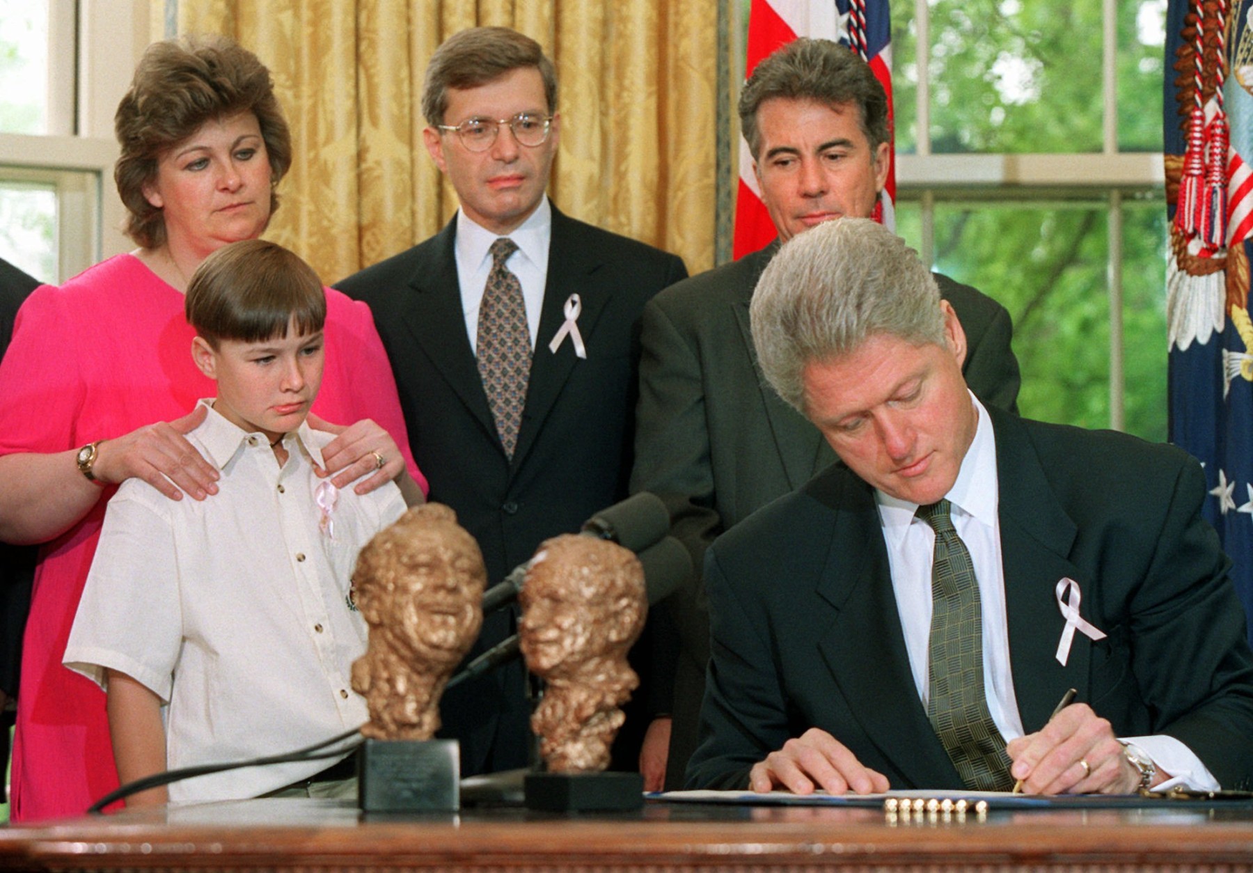 President Clinton signs the "Megan's Law," named after the late Megan Kanka of Hamilton Township, N.J., Friday May 17, 1996 in the Oval Office of the White House. Looking on from left are, Megan's mother Maureen, brother Jeremy, 7, Rep. Dick Zimmer, R-N.J., and John Walsh, host of the "America's Most Wanted" television show. (AP Photo/Denis Paquin)