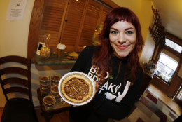 In this Nov. 20, 2014 photo made with a fisheye lens, Megh Villareal holds up a Marijuana-infused pecan pie at a holiday get-together for recreational marijuana vendors in east Denver. (AP Photo/David Zalubowski)