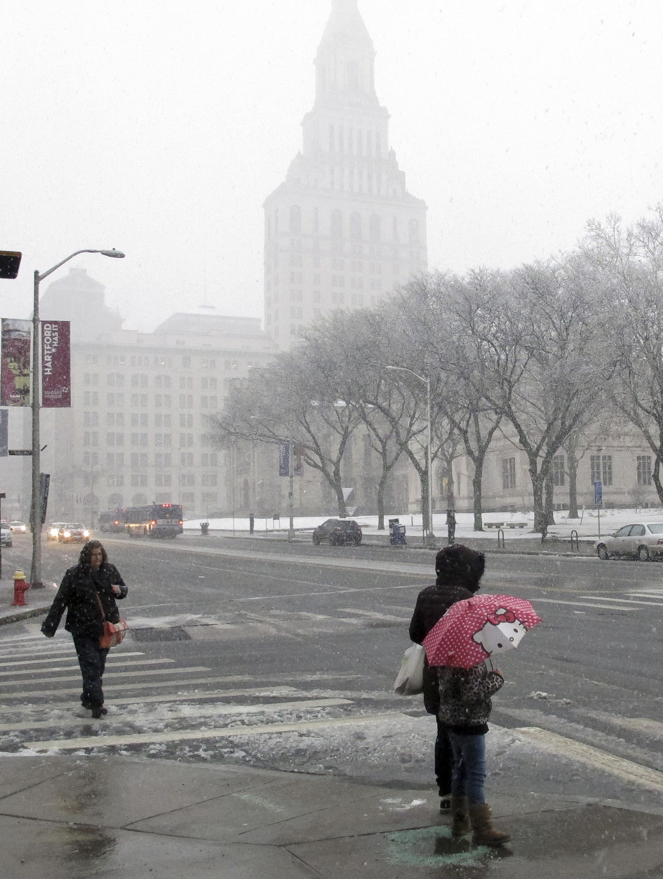 The Travelers tower is partially obscured by falling snow on Main Street in Hartford, Conn., on Friday, Feb. 5, 2016. The storm slowed the morning commute, prompted school closings and forced flight cancellations and delays. (AP Photo/Dave Collins)