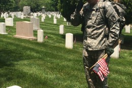 A soldier salutes in front of a grave marker at Arlington National Cemetery on Thursday, May 26, 2016. Before Memorial Day weekend each year, soldiers place hundreds of thousands of flags at the cemetery to honor fallen soldiers. (WTOP/Rachel Nania)