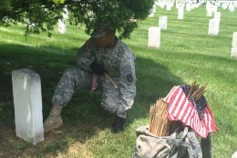 A soldier uses his boot to measure the placement of an American flag in front of a grave marker at Arlington National Cemetery on Thursday, May 26, 2016. Before Memorial Day weekend each year, the Old Guard places hundreds of thousands of flags at the cemetery to honor fallen soldiers. (WTOP/Rachel Nania)