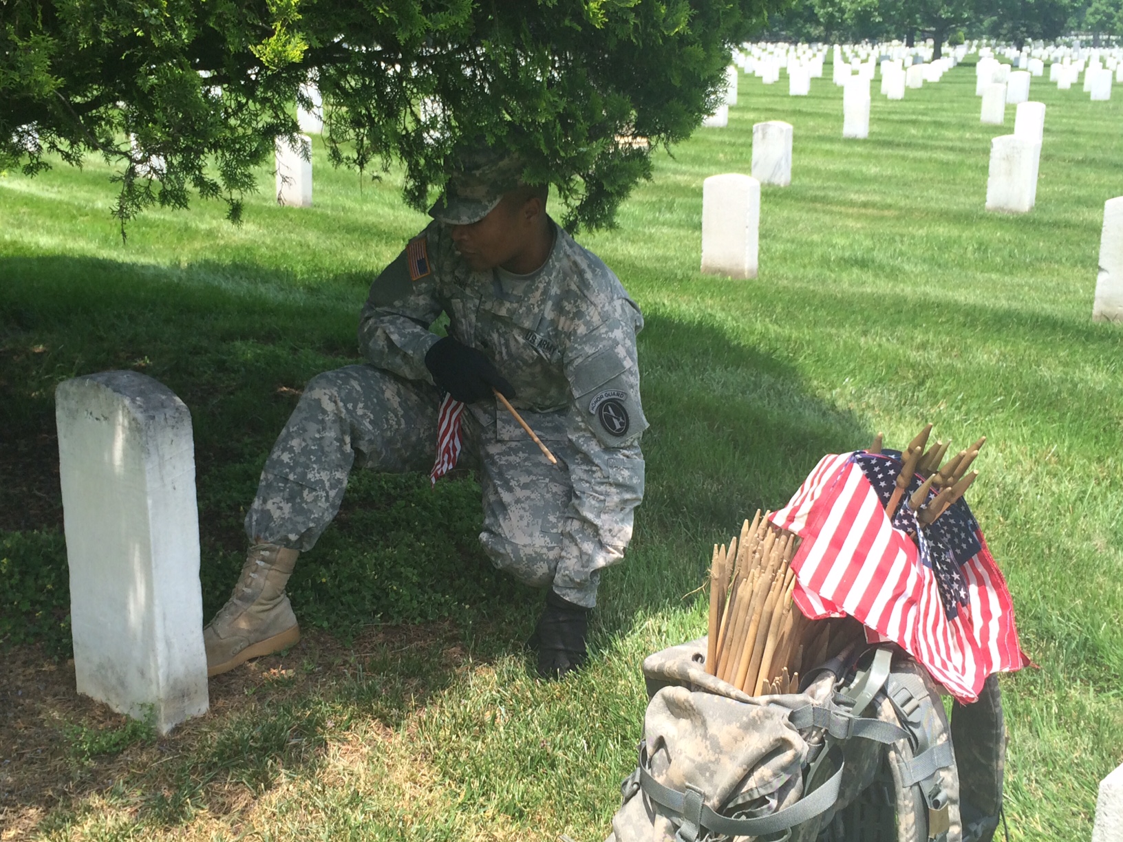 A soldier uses his boot to measure the placement of an American flag in front of a grave marker at Arlington National Cemetery on Thursday, May 26, 2016. Before Memorial Day weekend each year, the Old Guard places hundreds of thousands of flags at the cemetery to honor fallen soldiers. (WTOP/Rachel Nania)