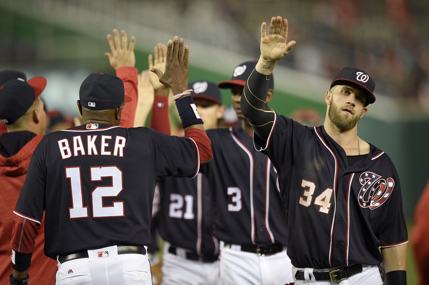 Washington Nationals' Bryce Harper (34), manager Dusty Baker (12) and others celebrate win over the Minnesota Twins after an interleague baseball game, Friday, April 22, 2016, in Washington. The Nationals won 8-4. (AP Photo/Nick Wass)