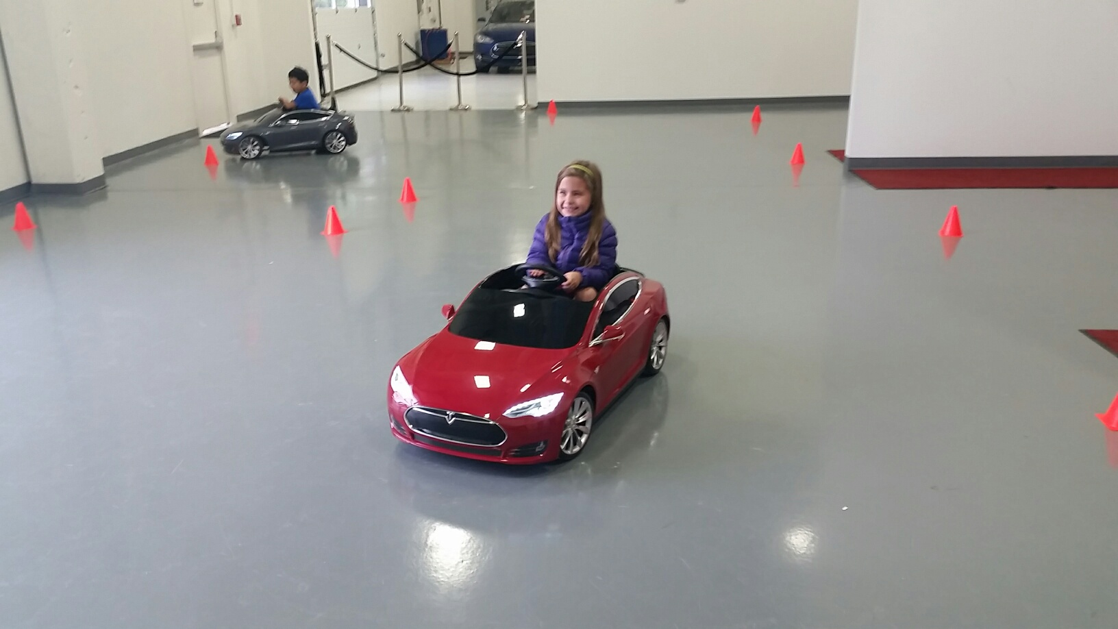 Kids take the Tesla Model S for Kids for a “road test” at Tesla Motors Tyco Road in Vienna, Va. on Sunday, May 22, 2016. (WTOP/Kathy Stewart)