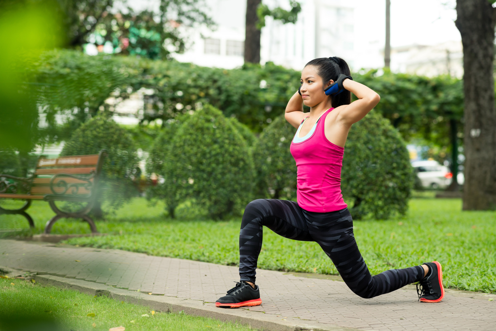 Fit Asian woman doing lunge exercise in park