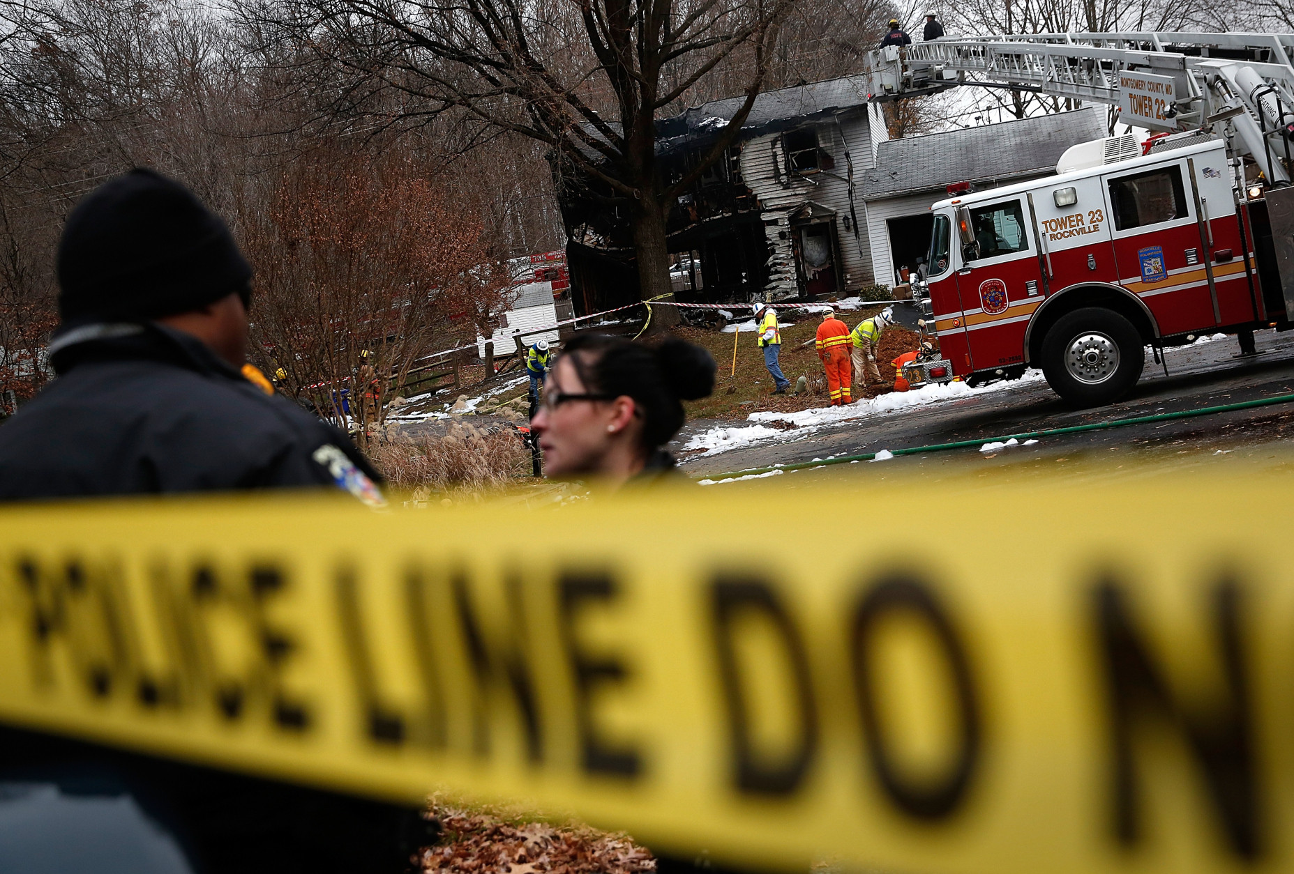 GAITHERSBURG, MD - DECEMBER 08:  Utility workers and emergency personnel work near the site where a small plane crashed into a residential neighborhood December 8, 2014 in Gaithersburg, Maryland. The three occupants of the plane were killed in the crash, and investigators are searching for three people who are unaccounted for on the ground.  (Photo by Win McNamee/Getty Images)