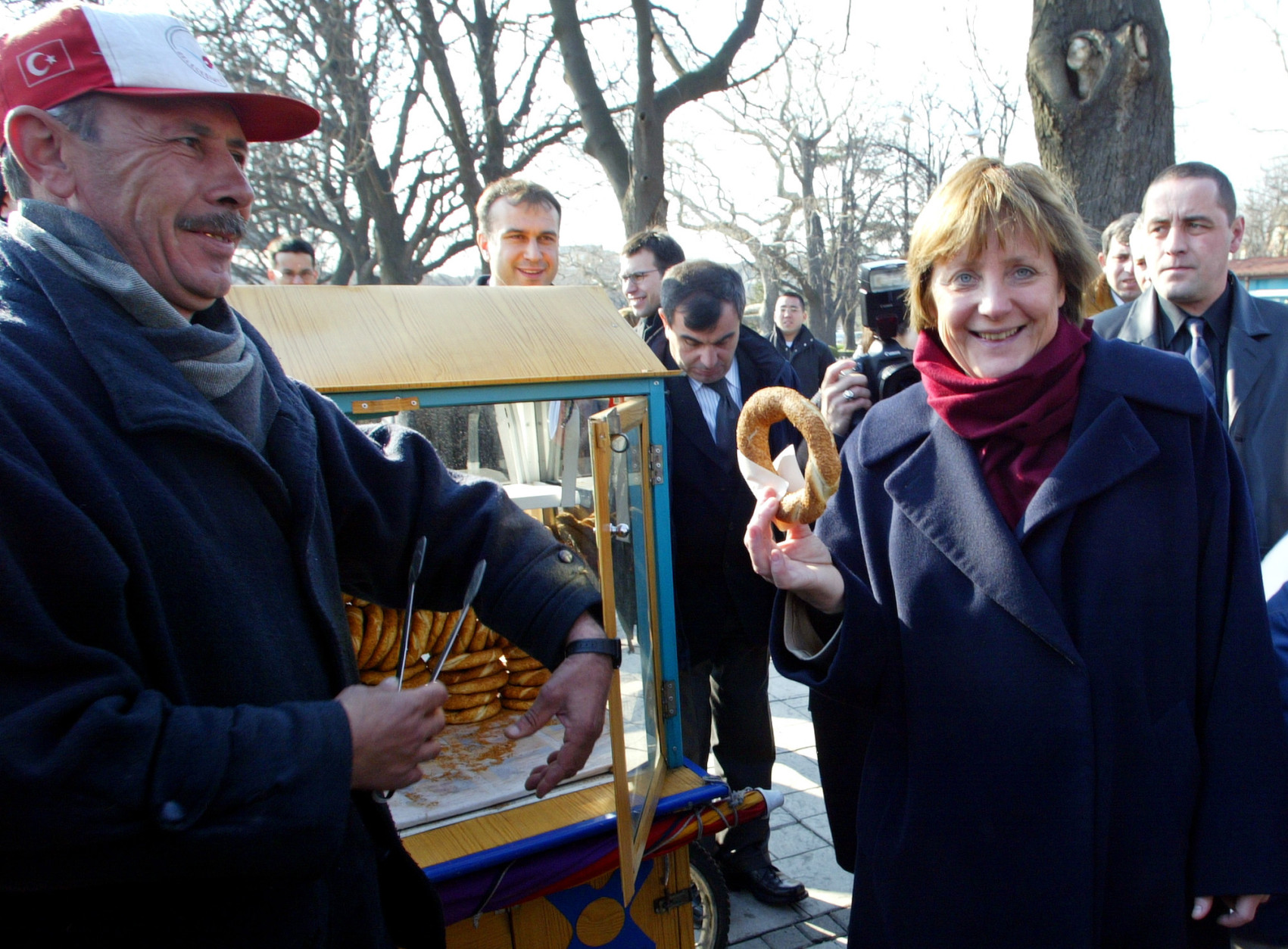 Angela Merkel, the leader of Germany's Christian Democrats, right, receives a simit, a traditional Turkish pretzel, from a street vendor as she tours Istanbul's old city, Turkey, Tuesday Feb. 17 , 2004. Angela Merkel is in Turkey for a two-day official visit. Merkel met with Turkish Prime Minister Recep Tayyip Erdogan and the other officials focusing on Turkey's European Union bid. (AP Photo/Osman Orsal)