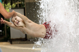 A boy gets a cool splash of a water fountain as he is swung by his mother at a park in Tokyo Monday, Aug. 13, 2007. Temperatures in Tokyo peaks in the low or mid 30s Celsius in the past several days.(AP Photo/Shizuo Kambayashi)