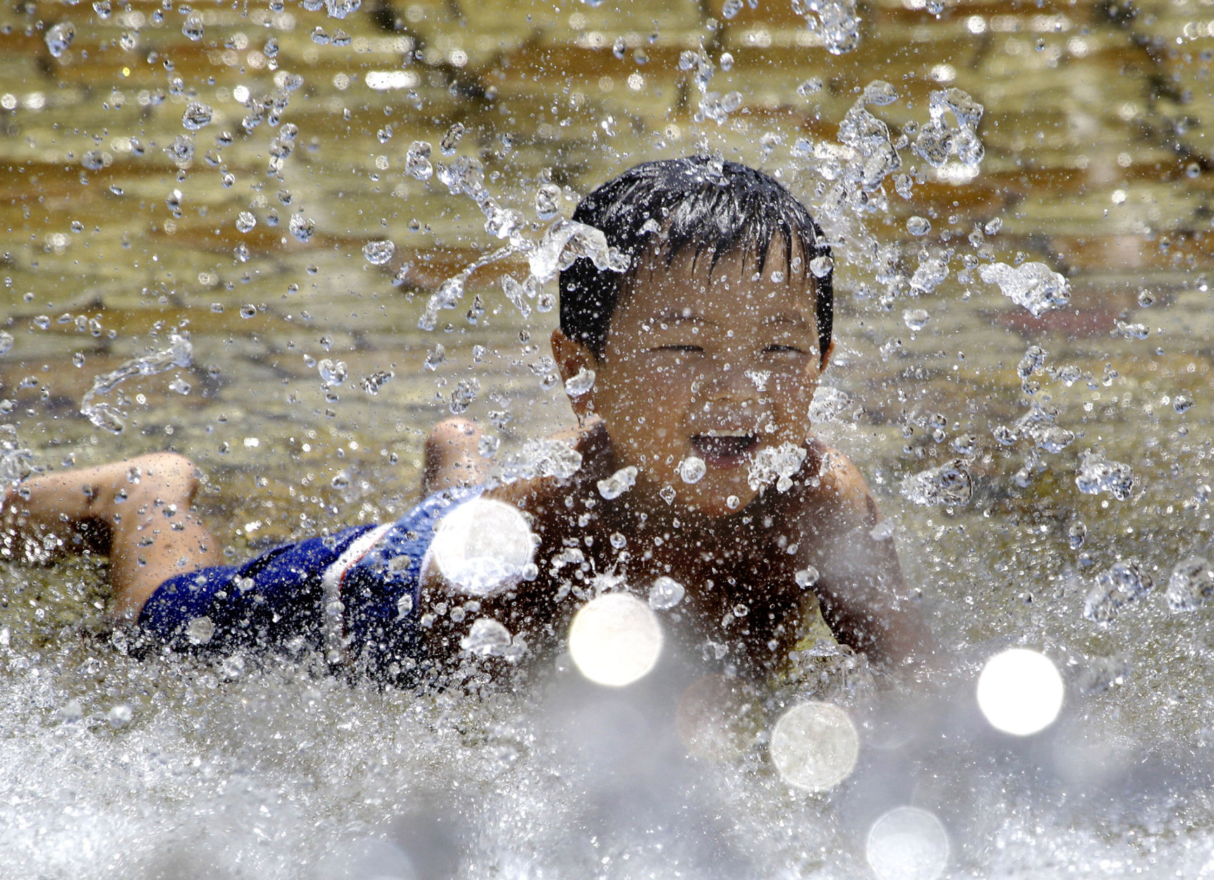 A boy tries to beat summer heat with splashed water at a Tokyo park Saturday, July 17, 2010. The Japan Meteorological Agency on Saturday said the temperature in central Tokyo shot up to 31 degrees Celsius (88 F) at noon as the weather men declared the rainy season seemed to be over in many parts of the nation, including the Tokyo area. (AP Photo/Koji Sasahara)