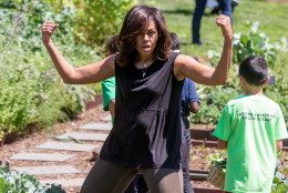 First lady Michelle Obama, joined by school children from across the country, jokingly flexes her muscles for members of the media as she harvests the White House Kitchen Garden, Monday, June 6, 2016, at the White House in Washington. (AP Photo/Andrew Harnik)