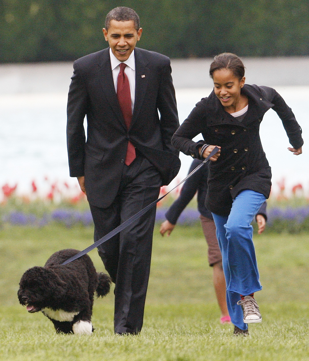 FILE - In this April 14, 2009 file photo, President Barack Obama watches as his daughter Malia walks their new dog Bo on the South Lawn of the White House in Washington. President Barack Obamas daughter Malia was just 10 and longing for a promised puppy when her family moved into the White House. Shes marked some of lifes milestones in the past seven years, and another one comes Friday: graduation from high school.  (AP Photo/Ron Edmonds, file)