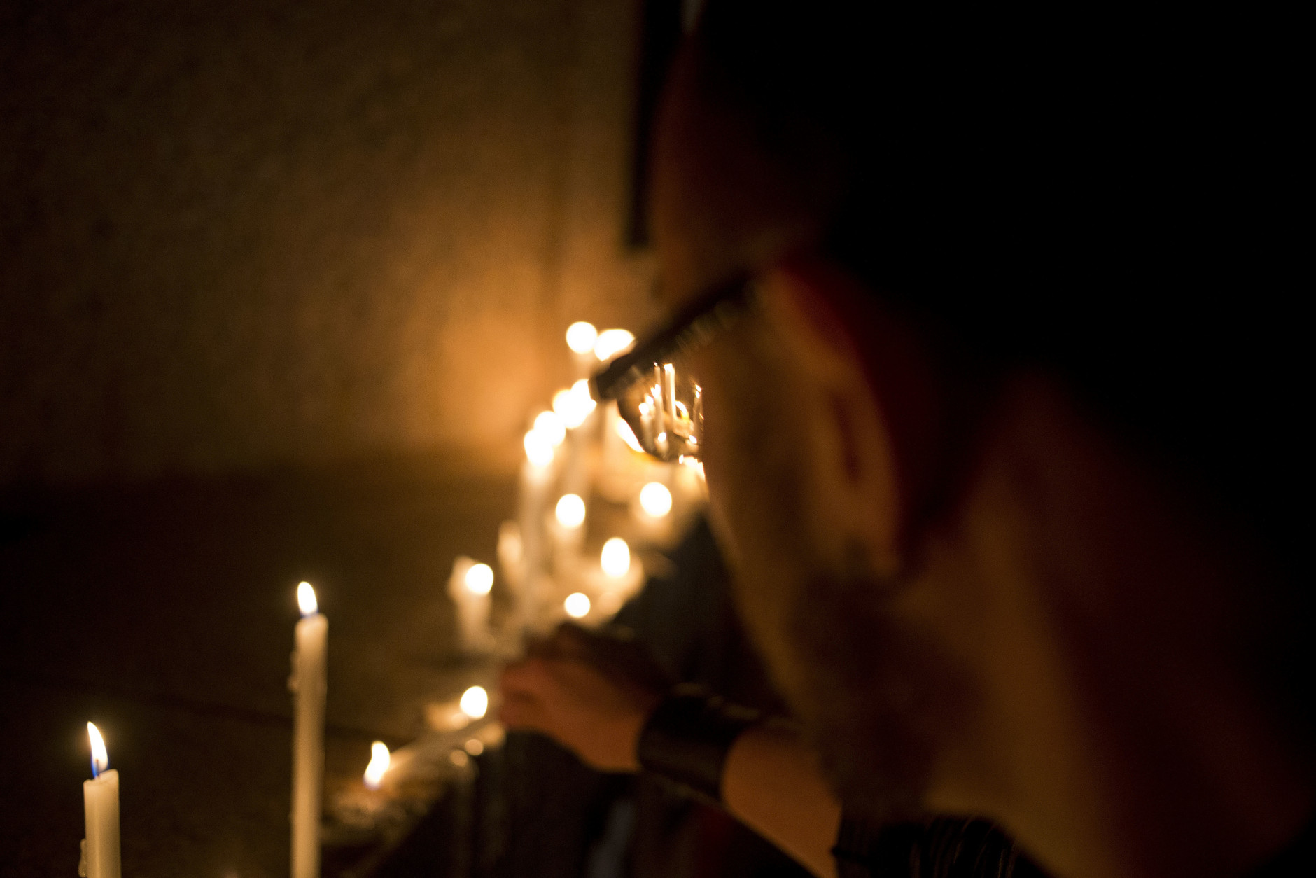 A man lights a light candle during a vigil in front of the U.S. embassy to remember the victims of the mass shooting at the Pulse, Orlando, Fla. nightclub, in Santiago, Chile, Sunday, June 12, 2016. A gunman opened fire inside the nightclub early Sunday, killing at least 50 people before dying in a gunfight with SWAT officers, police said. (AP Photo/Esteban Felix)