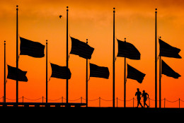 Runners pass under the the flags flying at half-staff around the Washington Monument at daybreak in Washington, Monday, June 13, 2016. The flags were ordered to half-staff by President Barack Obama to honor the victims of the Orlando nightclub shootings. (AP Photo/J. David Ake)