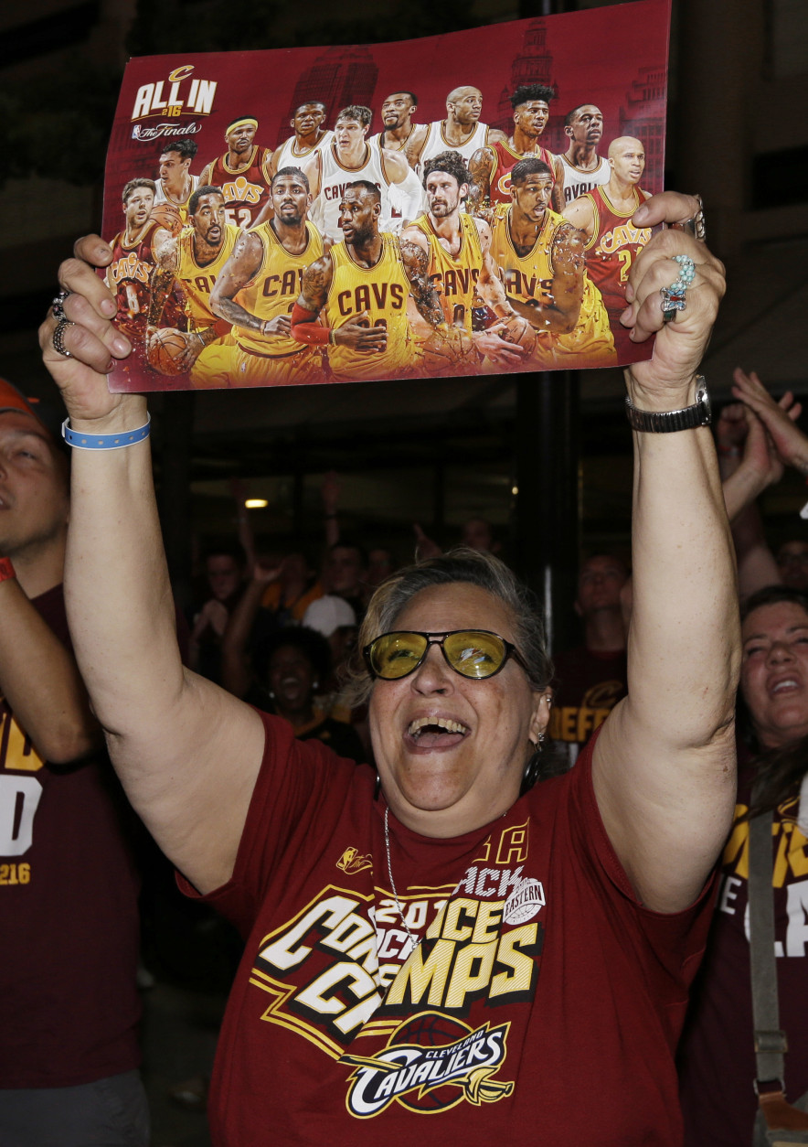 A woman holds up a poster of the Cleveland Cavaliers during a watch party for Game 7 of the NBA basketball Finals, Sunday, June 19, 2016, in Cleveland. (AP Photo/Tony Dejak)