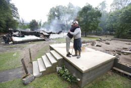 Jimmy Scott gets a hug from Anna May Watson, left, as they clean up from severe flooding in White Sulphur Springs, W. Va., Friday, June 24, 2016. A deluge of 9 inches of rain on parts of West Virginia destroyed or damaged more than 100 homes and knocked out power to tens of thousands of homes and businesses.  Scott lost his home to the flood and a fire that consumed his and the homes of several relatives. (AP Photo/Steve Helber)