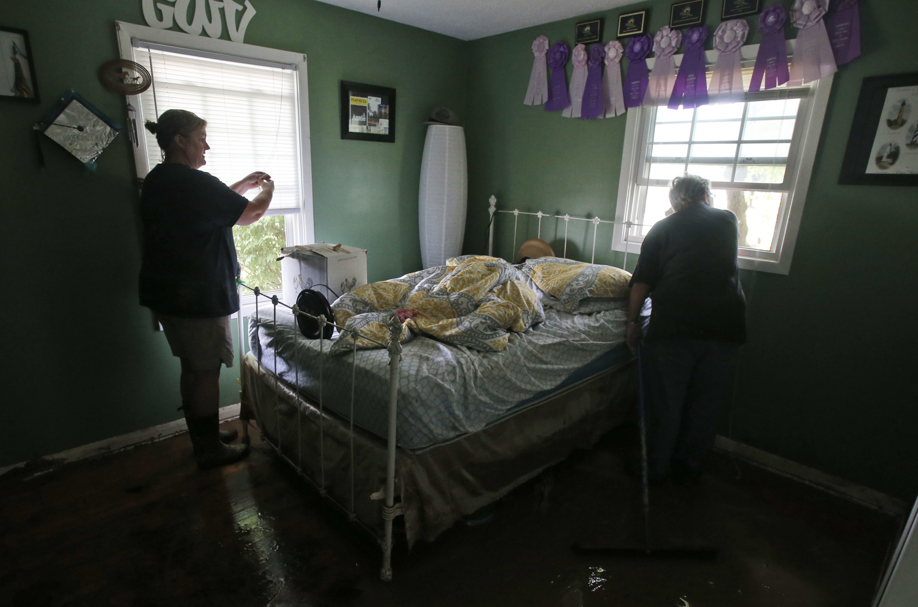 Kelly Vaughan, left, looks over flood damaged belongings in her fathers home with a neighbor as they clean up from severe flooding in White Sulphur Springs, W. Va., Friday, June 24, 2016. There were several fatalities around the state. (AP Photo/Steve Helber)