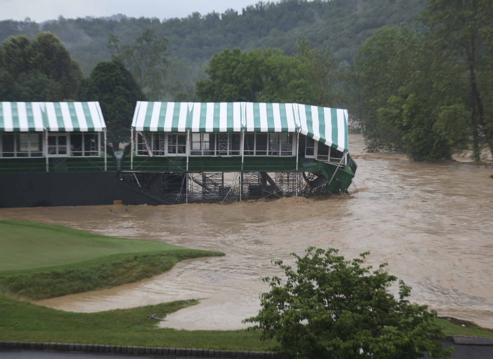 This Thursday June 23, 2016 image provided by the Greenbrier shows flooding on the 18th green of the Old White Course at the Greenbrier in White Sulphur Springs, W. Va. Severe flooding hit the area that is scheduled to host a PGA tour event in two weeks. (Cam Huffman/The Greenbrier via AP)