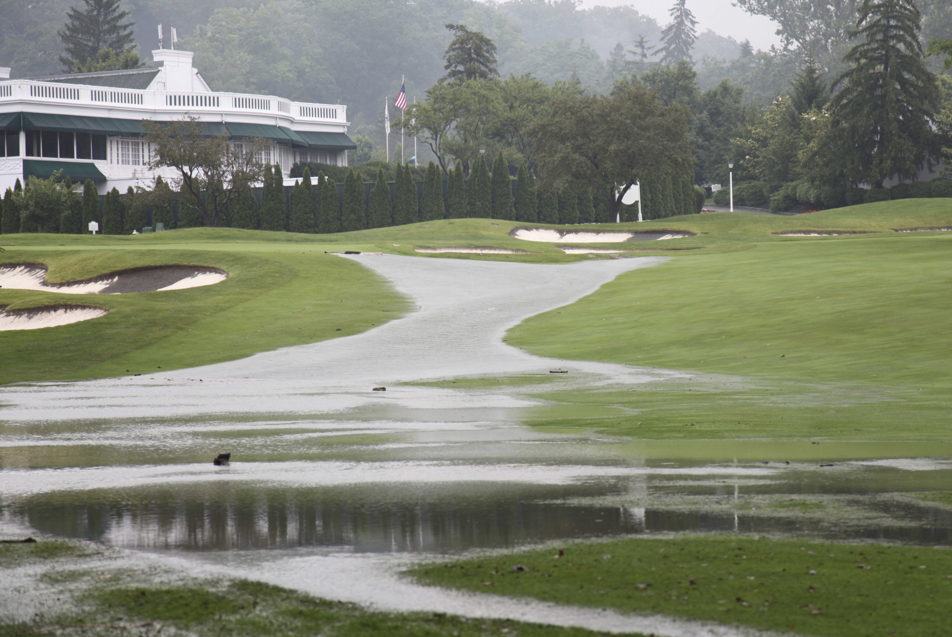 This Thursday June 23, 2016 image provided by the Greenbrier shows flooding on a fairway in front of the clubhouse of the Old White Course at the Greenbrier in White Sulphur Springs, W. Va. Severe flooding hit the area that is scheduled to host a PGA tour event in two weeks. (Harry Watson/The Greenbrier via AP)
