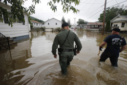 West Virginia State Trooper C.S. Hartman, left, and Bridgeport W.Va. fireman, Ryan Moran, wade through flooded streets as they search homes in Rainelle, W. Va., Saturday, June 25, 2016.  Teams were rescuing people from second-story windows, the hoods of cars and the tops of trees as floodwaters drenched southeastern West Virginia.   (AP Photo/Steve Helber)
