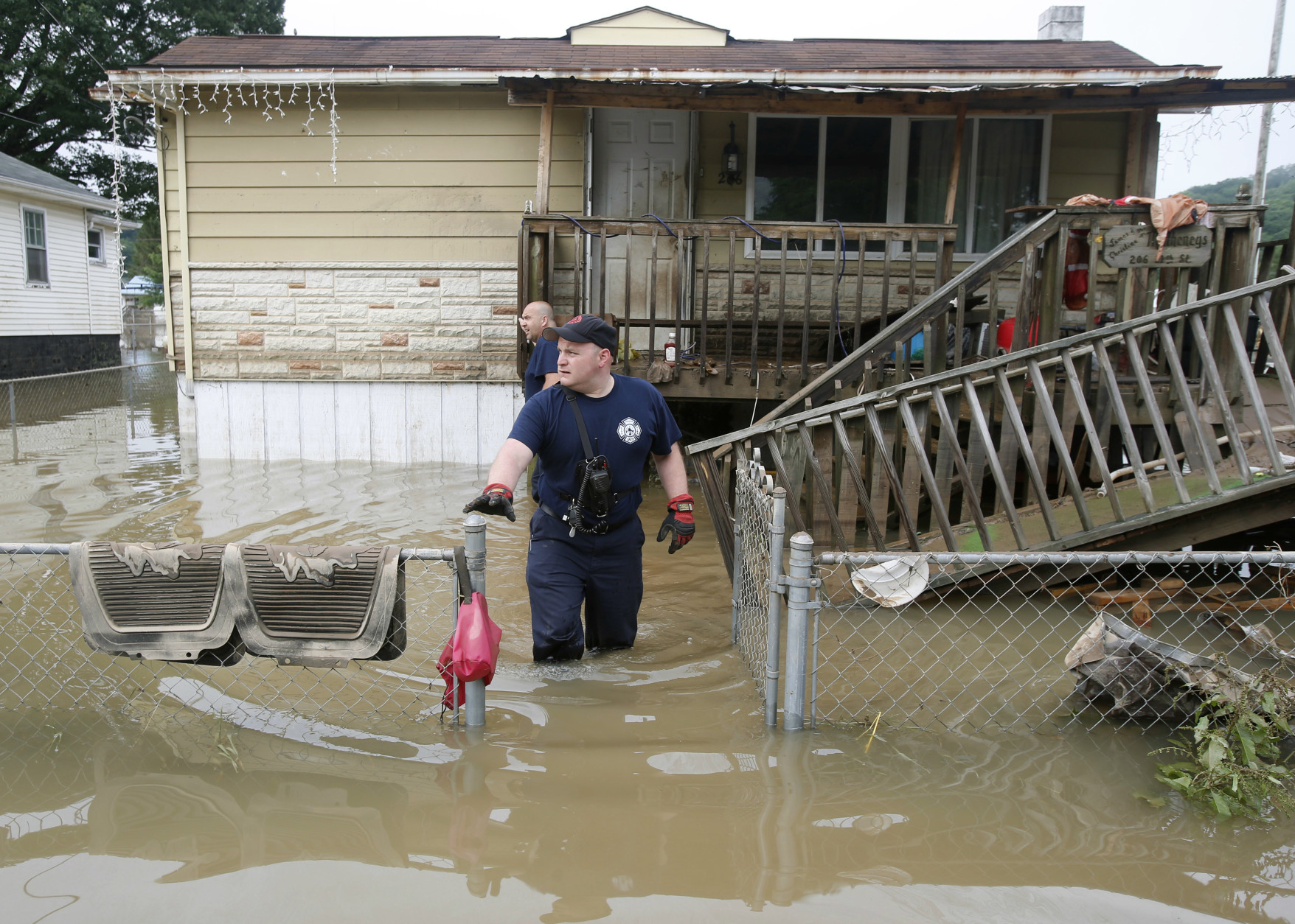 Bridgeport W.Va. fireman, Ryan Moran, exits a home as he and a crew search homes in Rainelle, W.Va., Saturday, June 25, 2016. Heavy rains that pummeled West Virginia left multiple people dead, and authorities said Saturday that an unknown number of people in the hardest-hit county remained unaccounted for.  (AP Photo/Steve Helber)