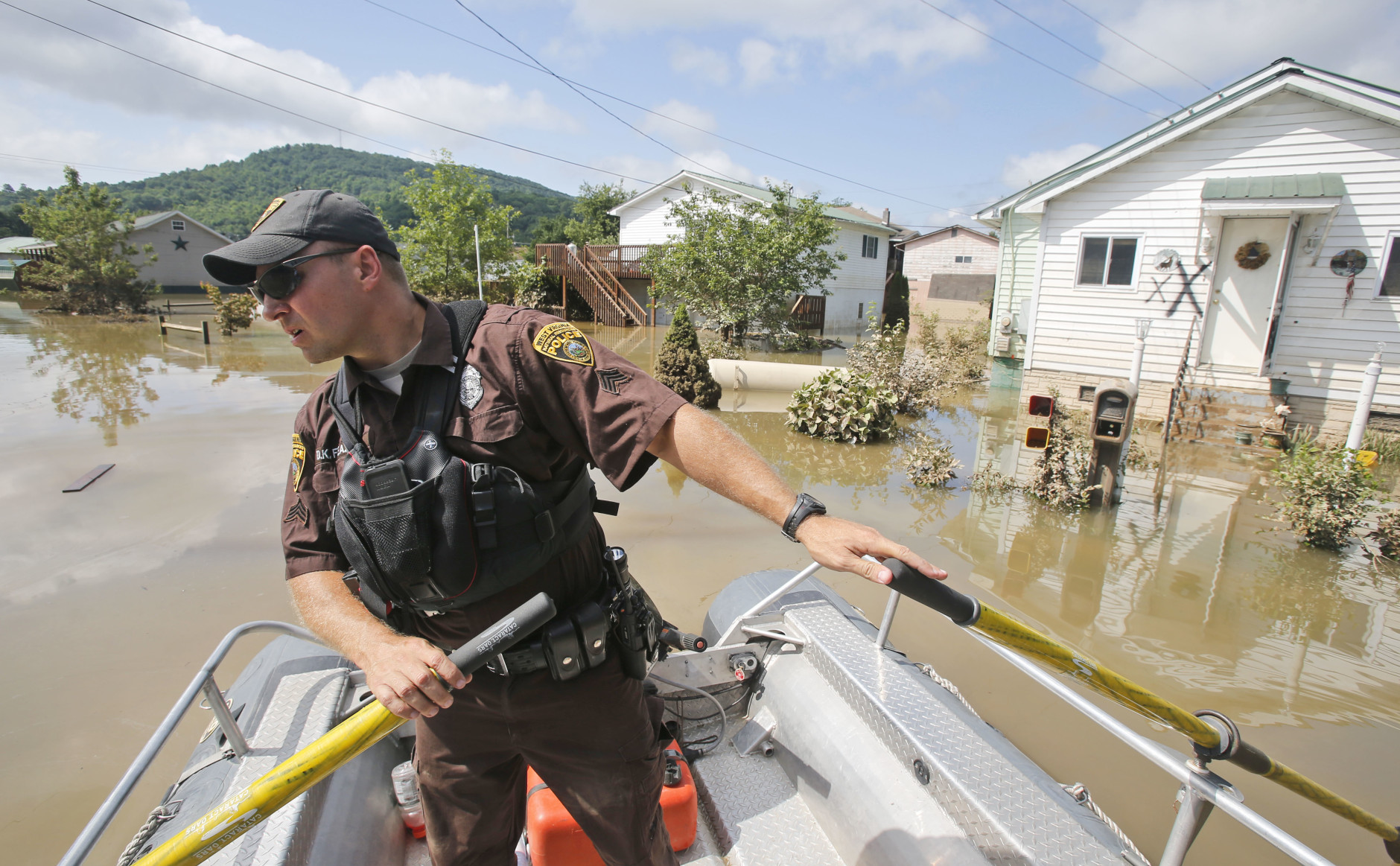 Lt. Dennis Feazell, of the West Virginia Department of Natural Resources, watches for debris as he and a co-worker search flooded homes in Rainelle, W. Va., Saturday, June 25, 2016. Heavy rains that pummeled West Virginia left multiple people dead, and authorities said Saturday that an unknown number of people in the hardest-hit county remained unaccounted for.  (AP Photo/Steve Helber)