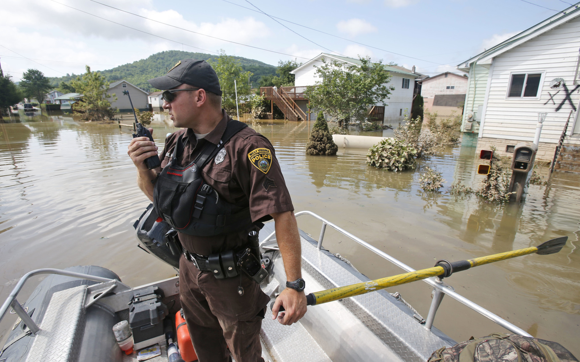 Lt. Dennis Feazell, of the West Virginia Department of Natural Resources, contacts his command center as he and a co-worker search flooded homes in Rainelle, W. Va., Saturday, June 25, 2016. Heavy rains that pummeled West Virginia left multiple people dead, and authorities said Saturday that an unknown number of people in the hardest-hit county remained unaccounted for.  (AP Photo/Steve Helber)