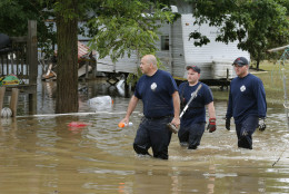 Bridgeport W.Va. firefighters, Steve Gallo, left, and Ryan Moran, center, are joined by an unidentified co-worker as they walk through a flooded street while searching homes in Rainelle, W. Va., Saturday, June 25, 2016.  Heavy rains that pummeled West Virginia left multiple people dead, and authorities said Saturday that an unknown number of people in the hardest-hit county remained unaccounted for. (AP Photo/Steve Helber)