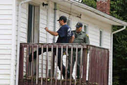 Bridgeport W. Va fireman Ben Tacy, left, kicks in the door of a flooded home under the supervision of State Trooper C.S. Hartman as they search homes in Rainelle, W. Va., Saturday, June 25, 2016. Heavy rains that pummeled West Virginia left multiple people dead, and authorities said Saturday that an unknown number of people in the hardest-hit county remained unaccounted for. (AP Photo/Steve Helber)